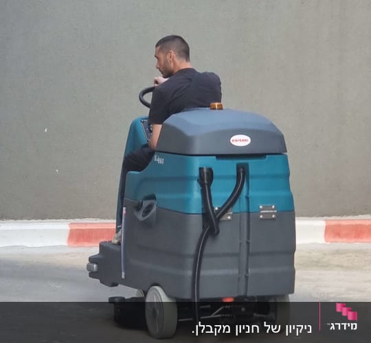 אדם נוהג במכונת שטיפה על כביש